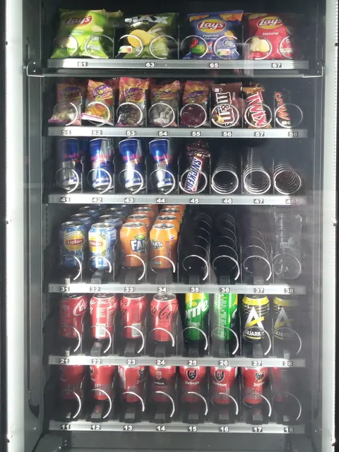 Drankautomaat met blikjes frisdrank, en bovenaan chips, snoep en chocolade